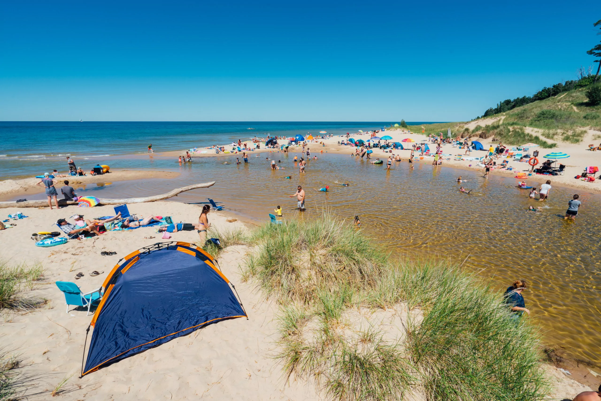 Crowds of people enjoy Muskegon Duck Lake State Park Beach on a sunny day.