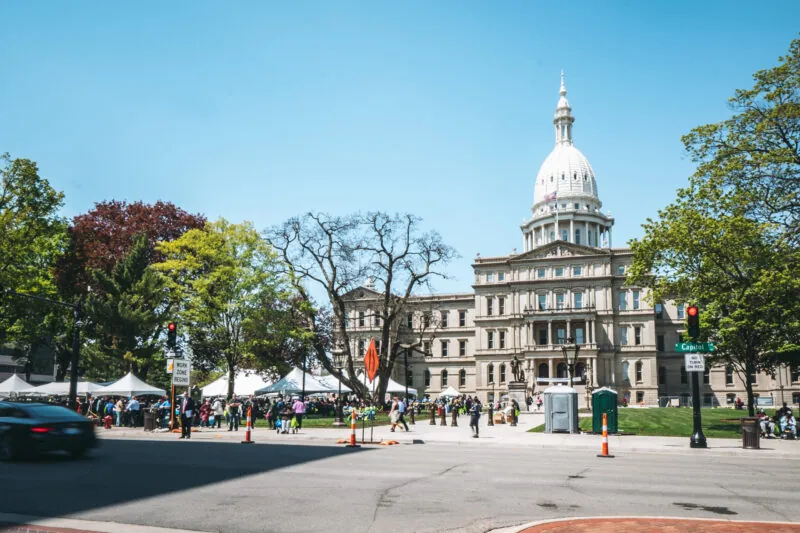 The Michigan Capitol building sits in a festive and populated square.