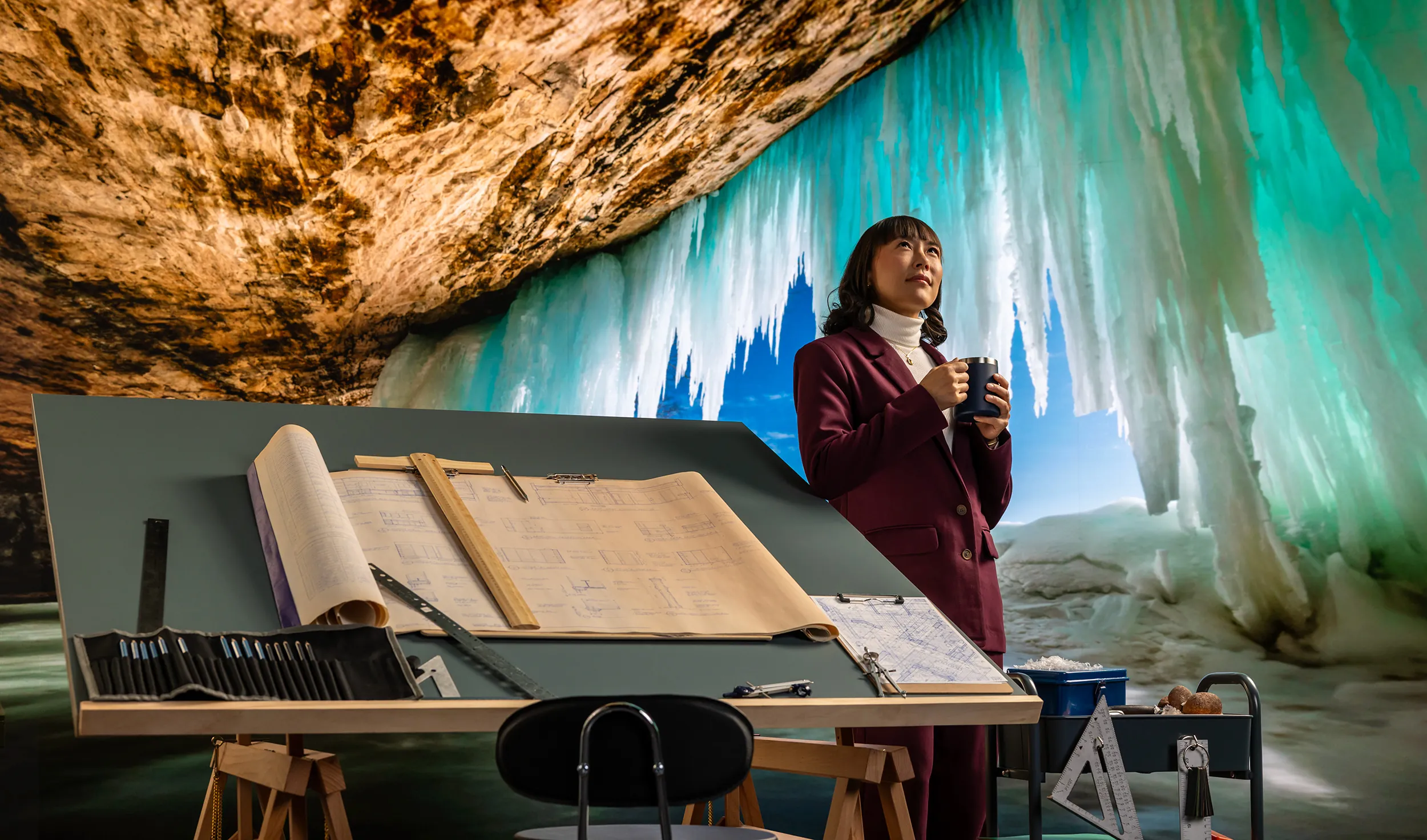 Woman with cup of coffee inside an ice cave with drafting table