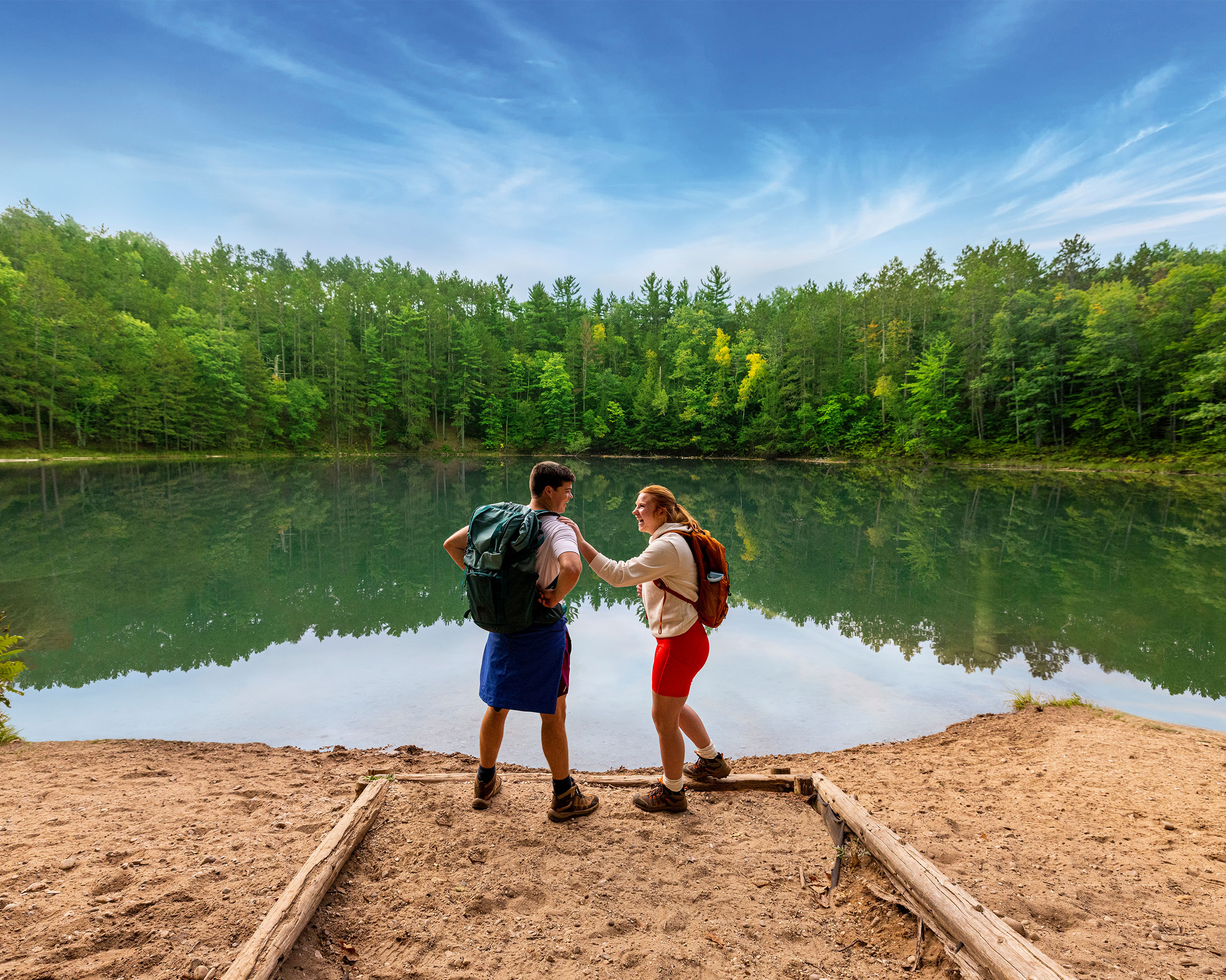 Man and women standing on sand in front of lake