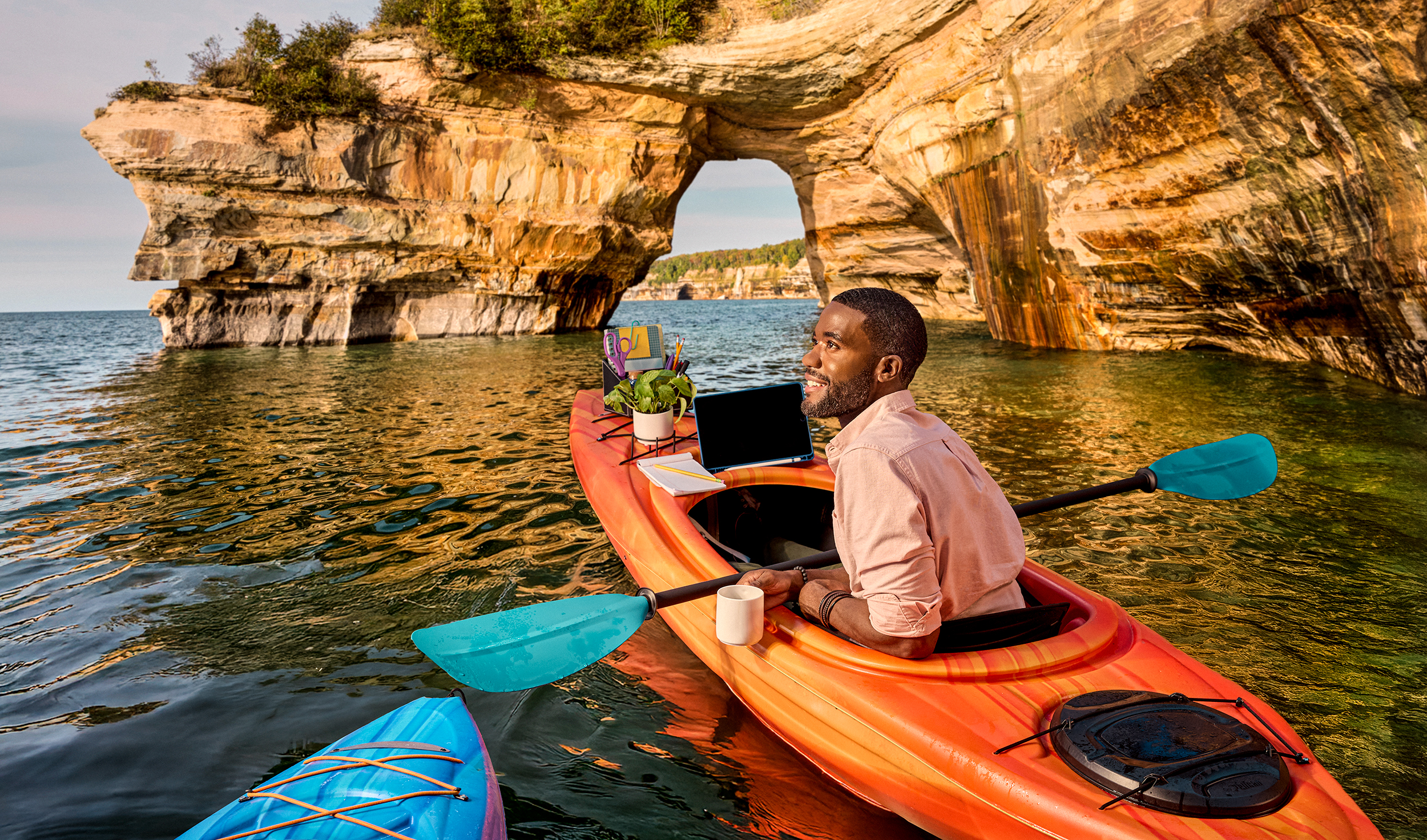 Man kayaking with cup of coffee and laptop computer at Pictured Rocks in Michigan