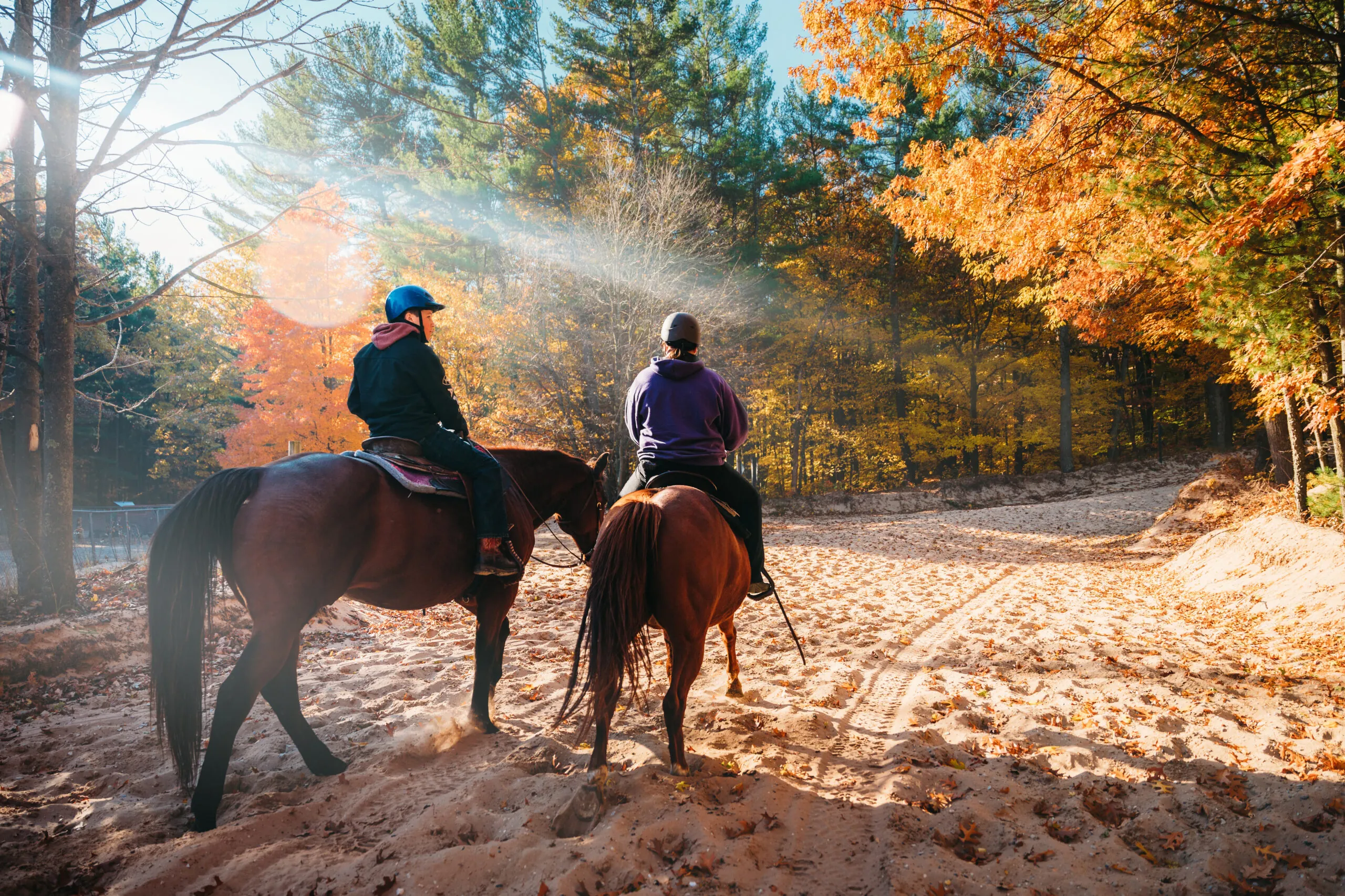 Couple rides horses through Silver Lake Sand Dunes in the fall.