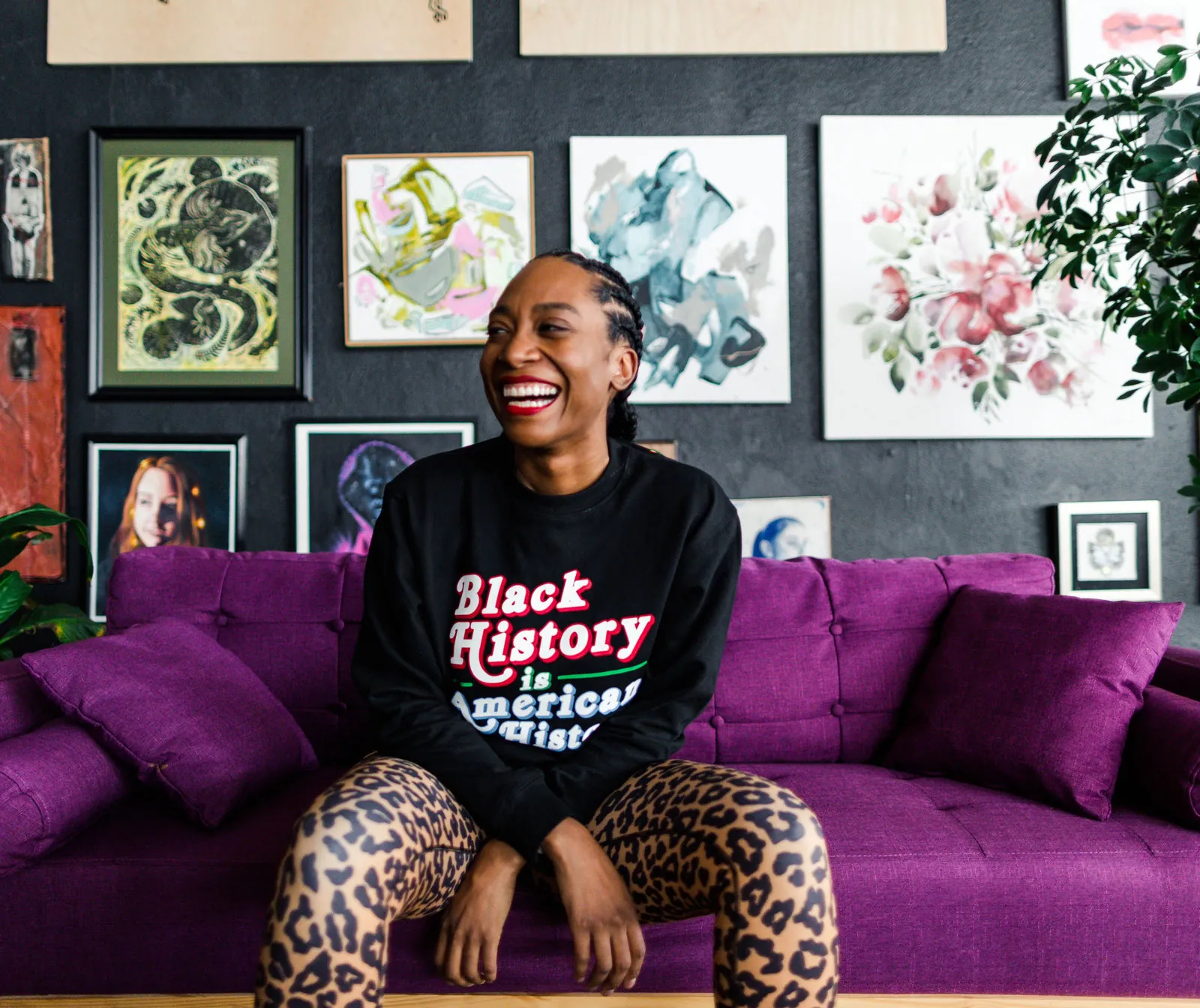 Dre Wallace, founder of OPNR, laughs while sitting on a fuchsia couch.