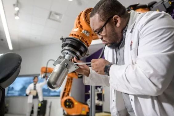 Male engineer tightens screw on robotic arm.