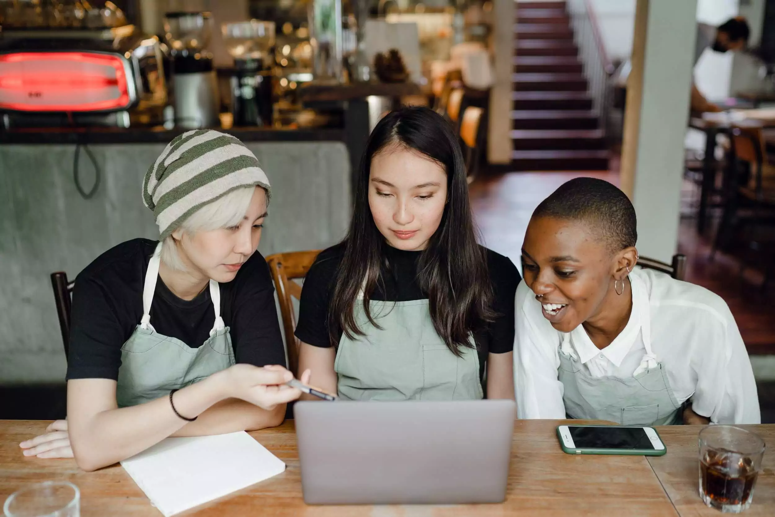Three young women discuss the business plan for their coffee shop.