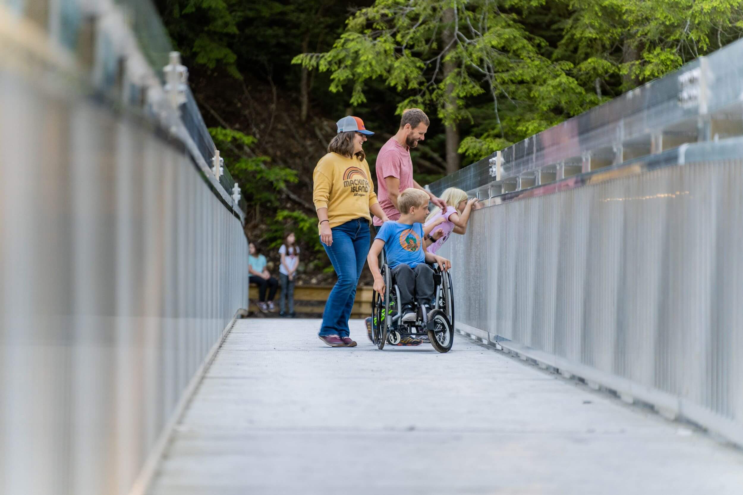 Family stands on bridge smiling down.