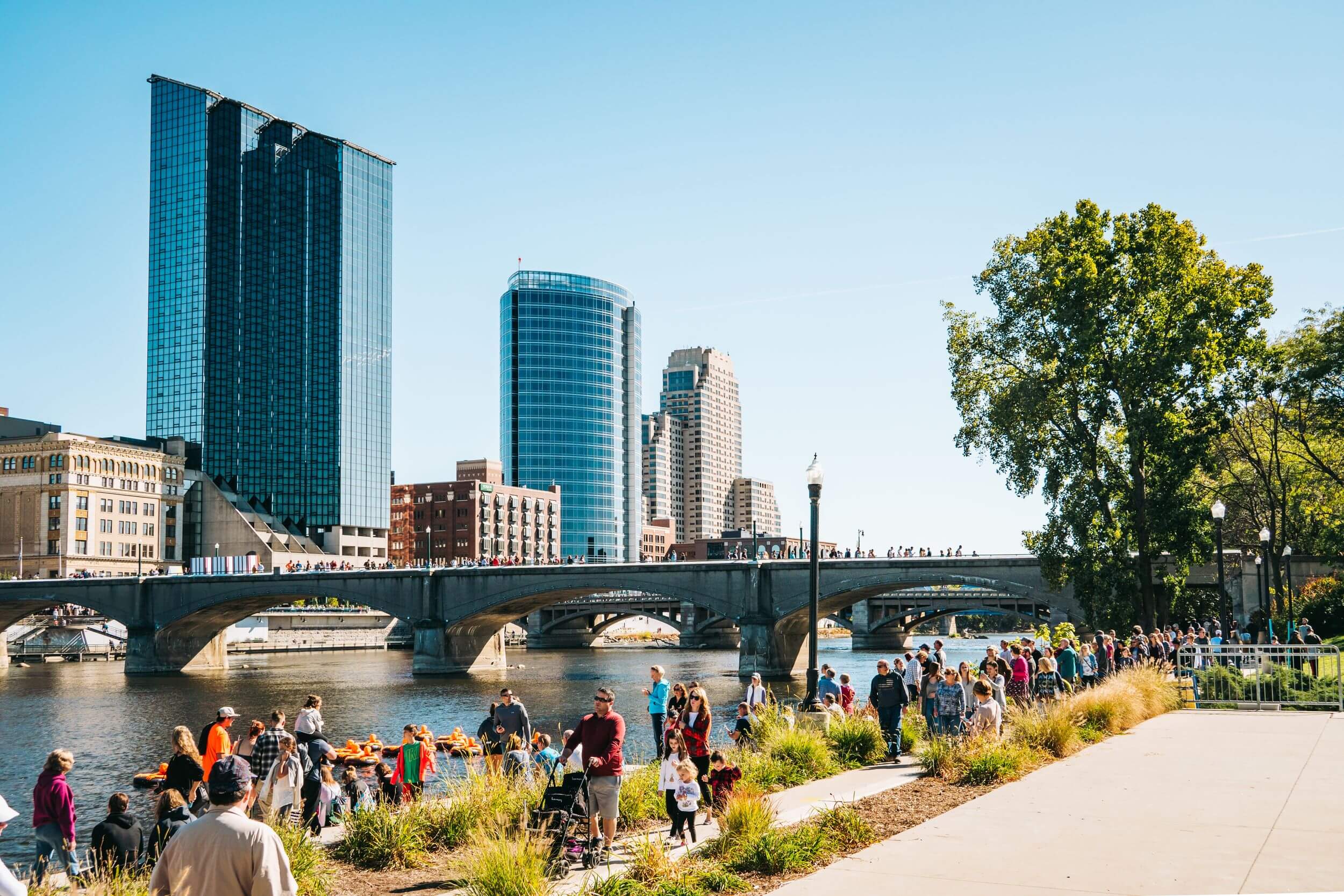 People walk along the river in downtown Grand Rapids in the summer.
