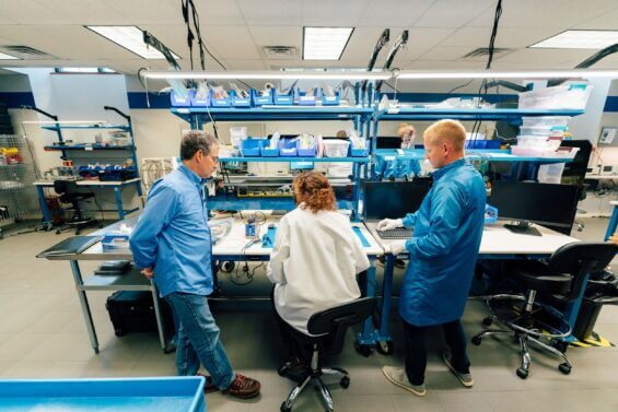 Three engineers work at lab bench at Orbion Space Technology.