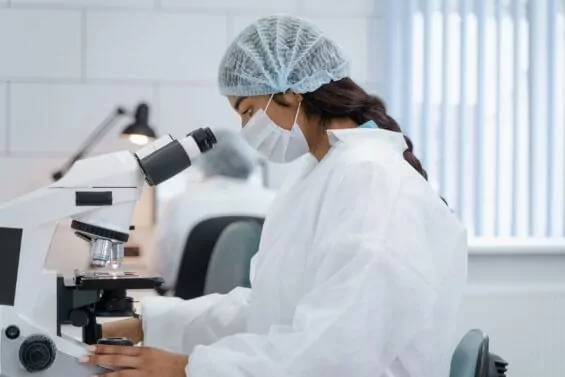 Female scientist working on microscope in lab.