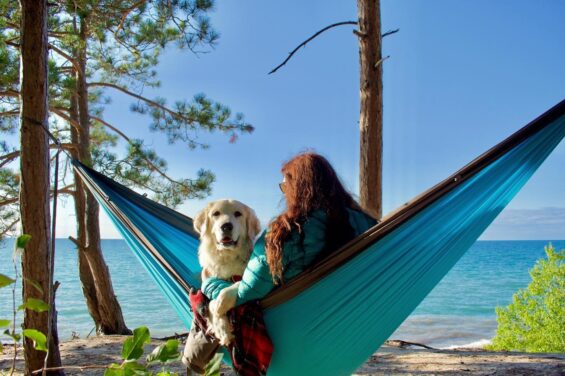 A woman with red hair relaxes in a hammock facing Lake Michigan, a large golden retriever in her lap.