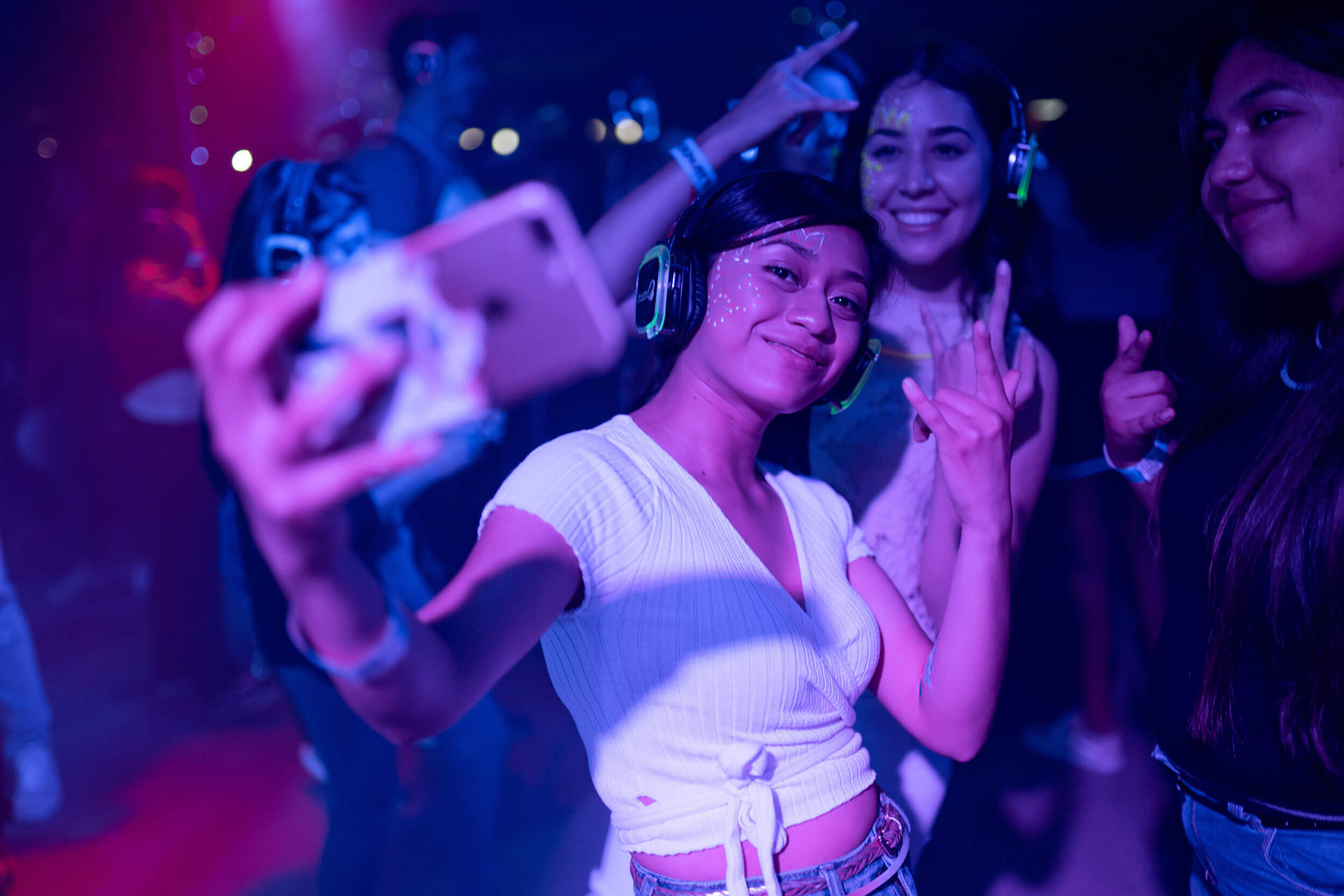 Group of friends with neon face paint take a selfie at a silent rave.