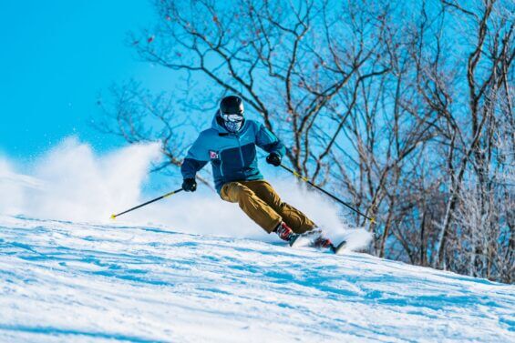Man skis down a slope at Caberfae Peaks on a sunny day.