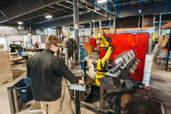 Man operates robotic arm at advanced manufacturing company.