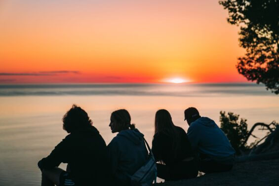 Four people watch the sunset at sleeping bear dunes overlook.